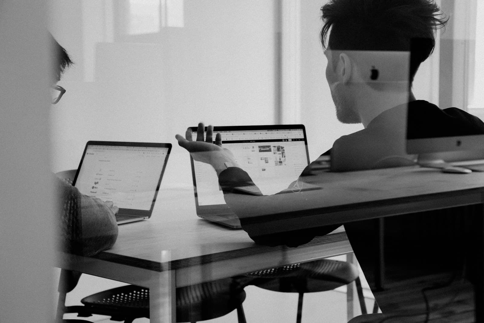 Two people working on laptops at a meeting table